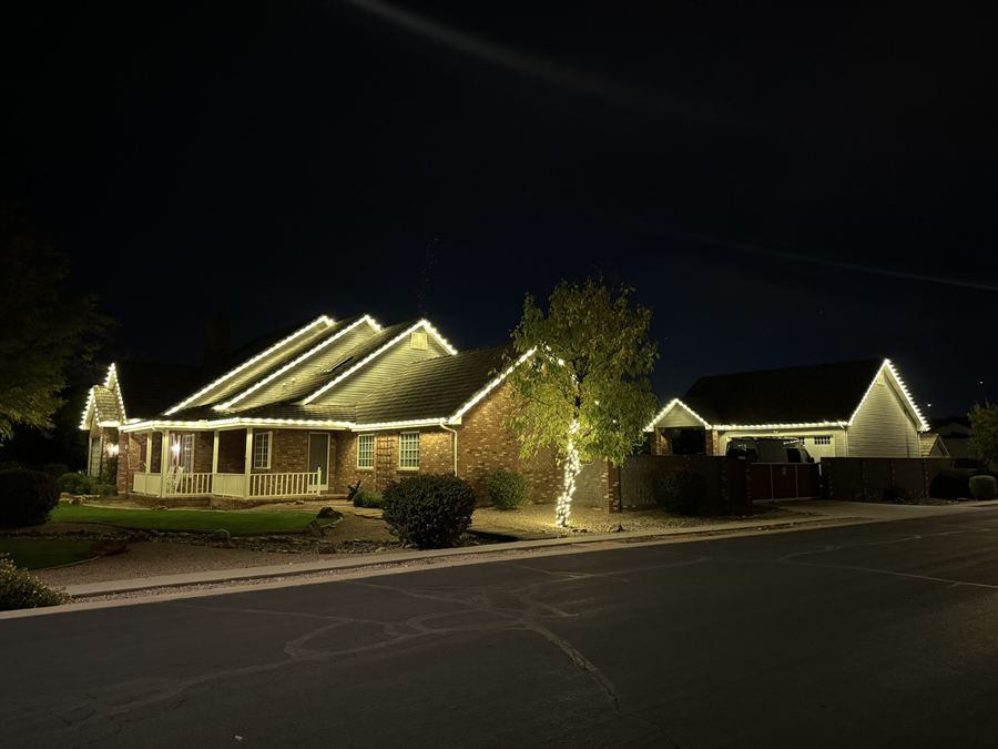 Brick ranch home with a warm white roofline and a lit tree
