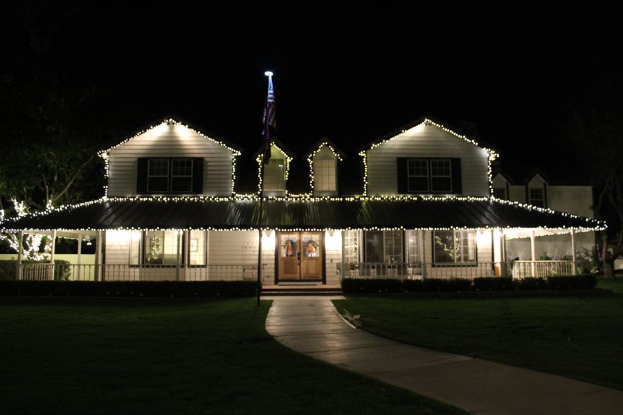 Farmhouse with a crisp white roofline and a lit front porch